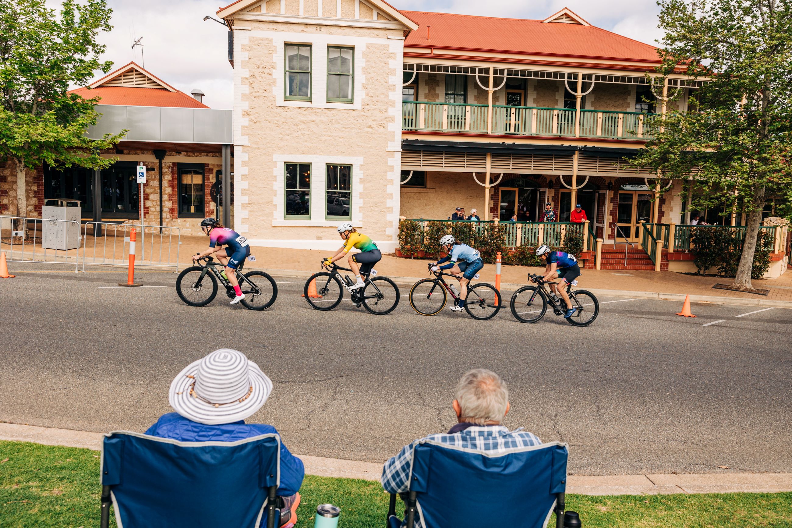 Four masters women cyclist climb up the Loxton Kicker while two spectators watch on in the criterium at the 2024 AusCycling Masters and Junior Road National Championships in Loxton