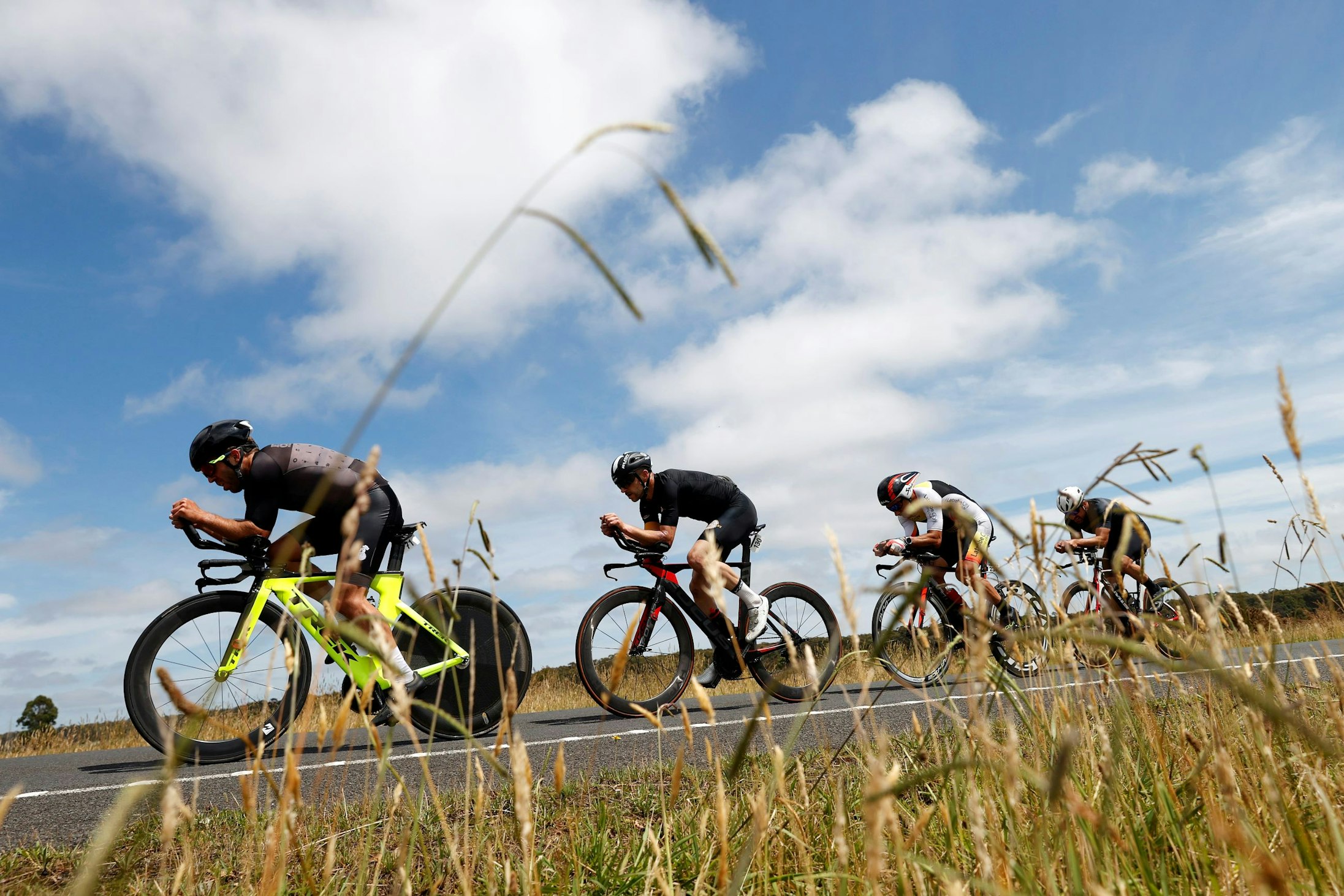 A team of four road cyclists pacing in a line during a team time trial at the 2024 Road National Championships in Ballarat under an idyllic blue sky