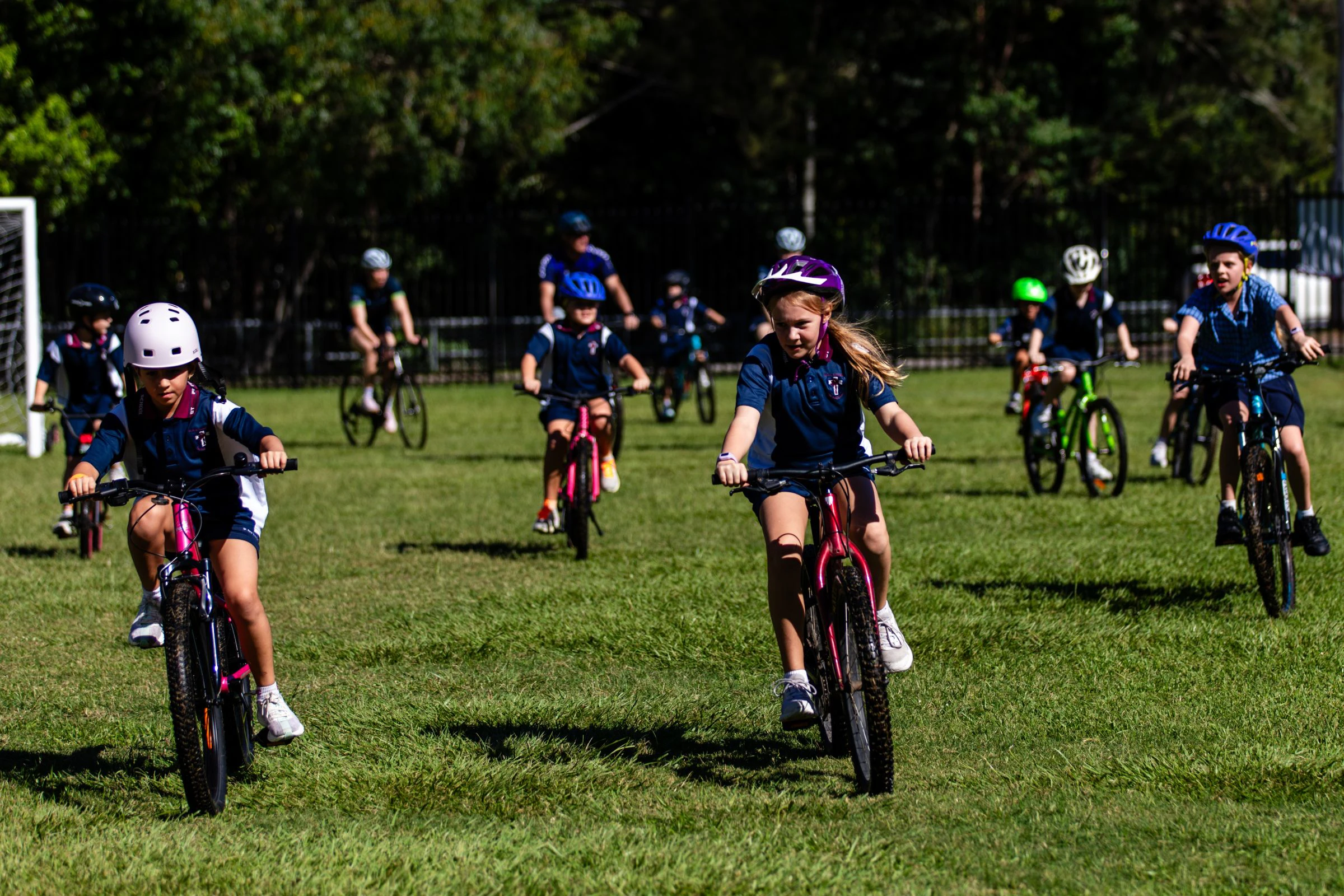 School students from St Peter Chanel Primary School in Brisbane ride their bicycles across the grassy field as part of 2026 National Ride2School Day and the Brisbane Cycling Festival