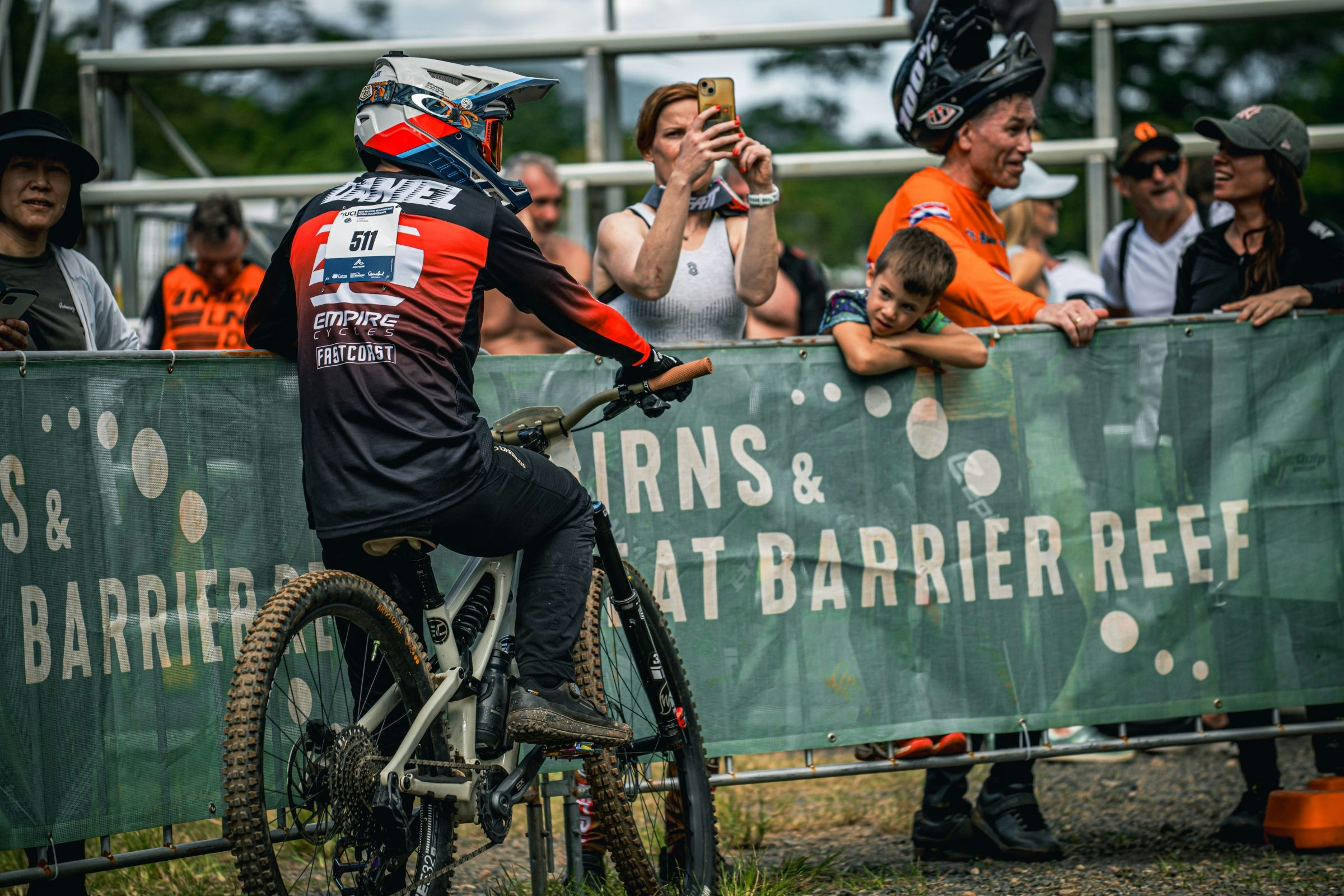 A Downhill racer leans on some Cairns and Great Barrier Reef fencing at the UCI Masters MTB World Championships in Cairns, 2025