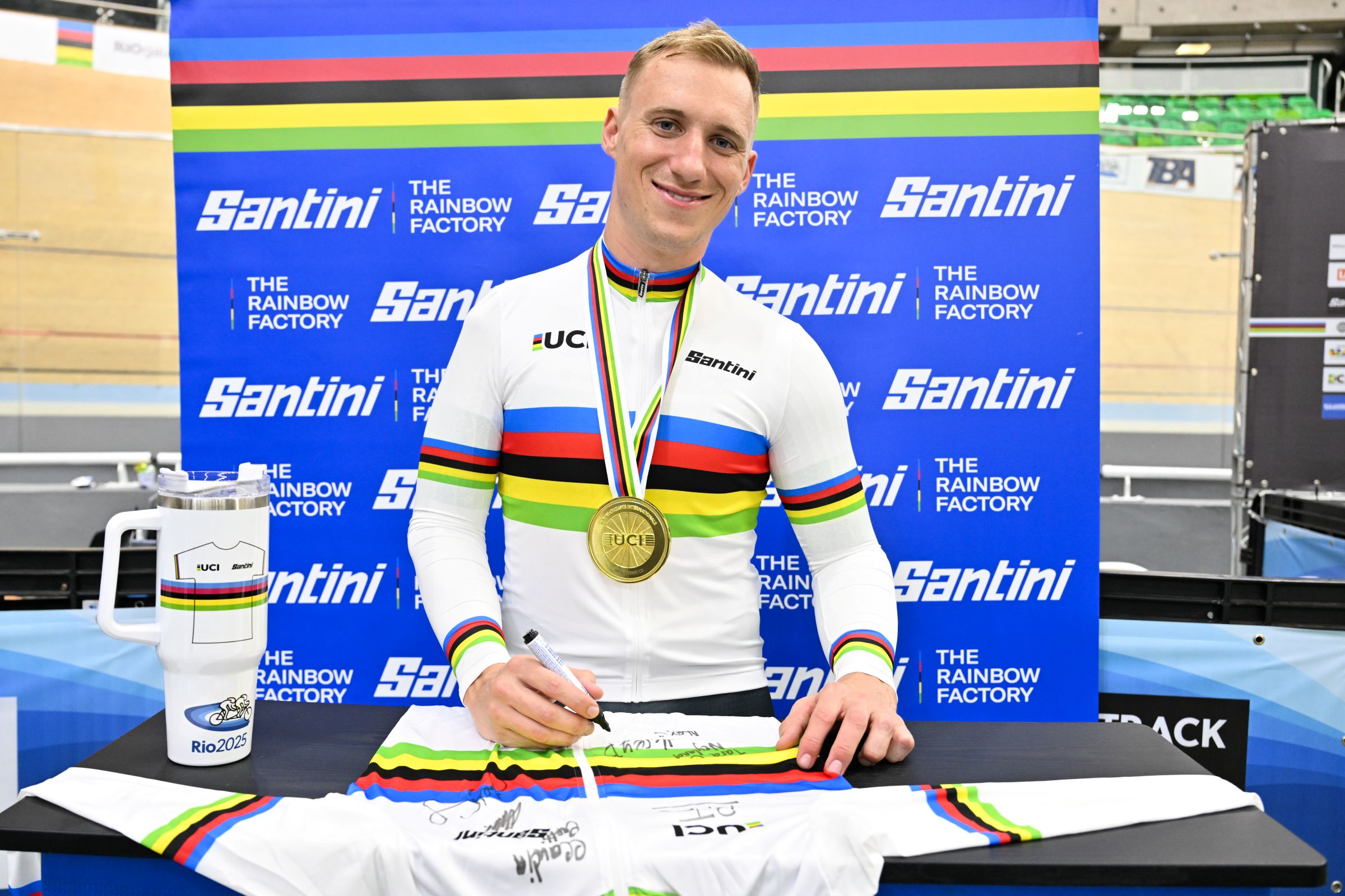 Korey Boddington in a rainbow jersey of UCI World Champion signing a rainbow jersey at the 2025 UCI Para-cycling Track World Championships in Rio de Janeiro