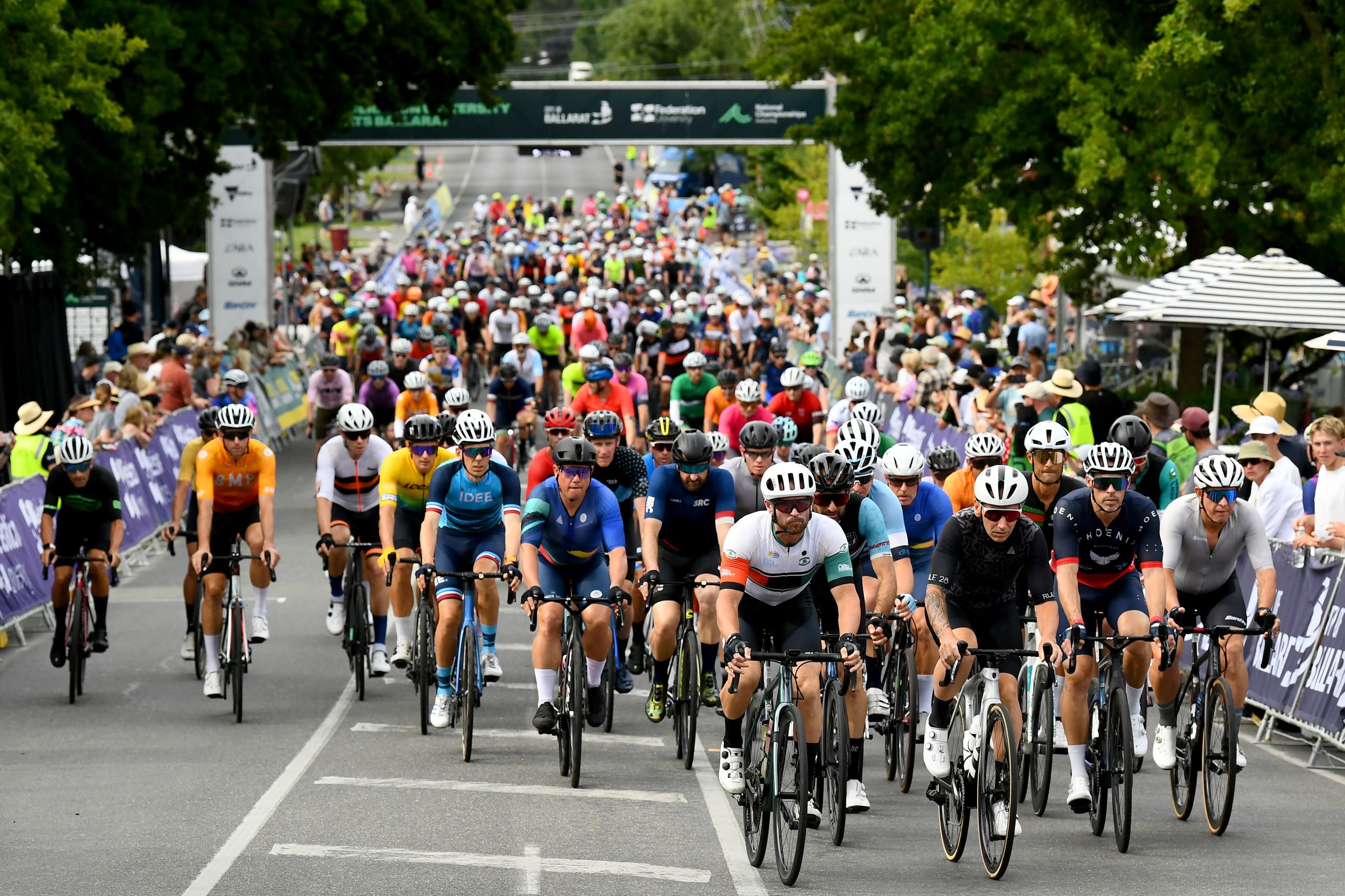 A large group of road cyclists ride from the start line at the 2024 AusCycling Gran Fondo National Championships at RoadNats Ballarat in Buninyong