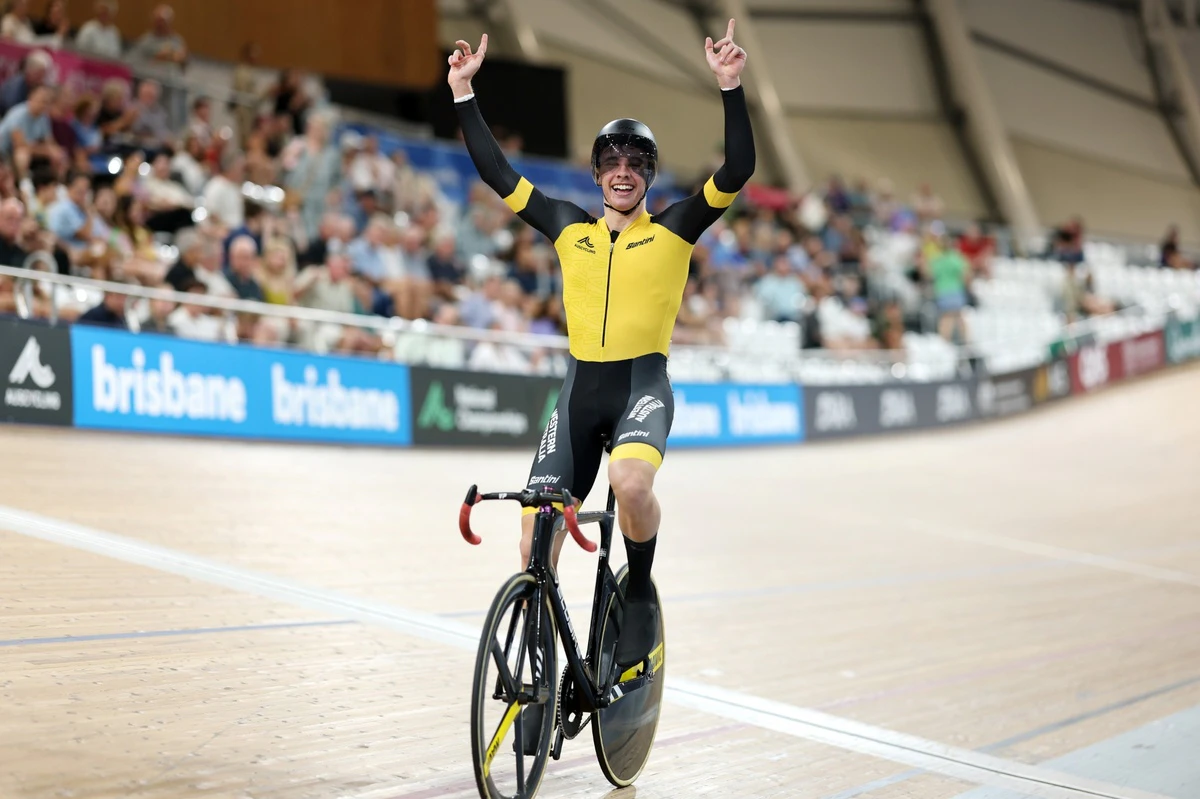 Cyclist celebrates victory with arms raised during a track cycling race at the National Championships in Brisbane.