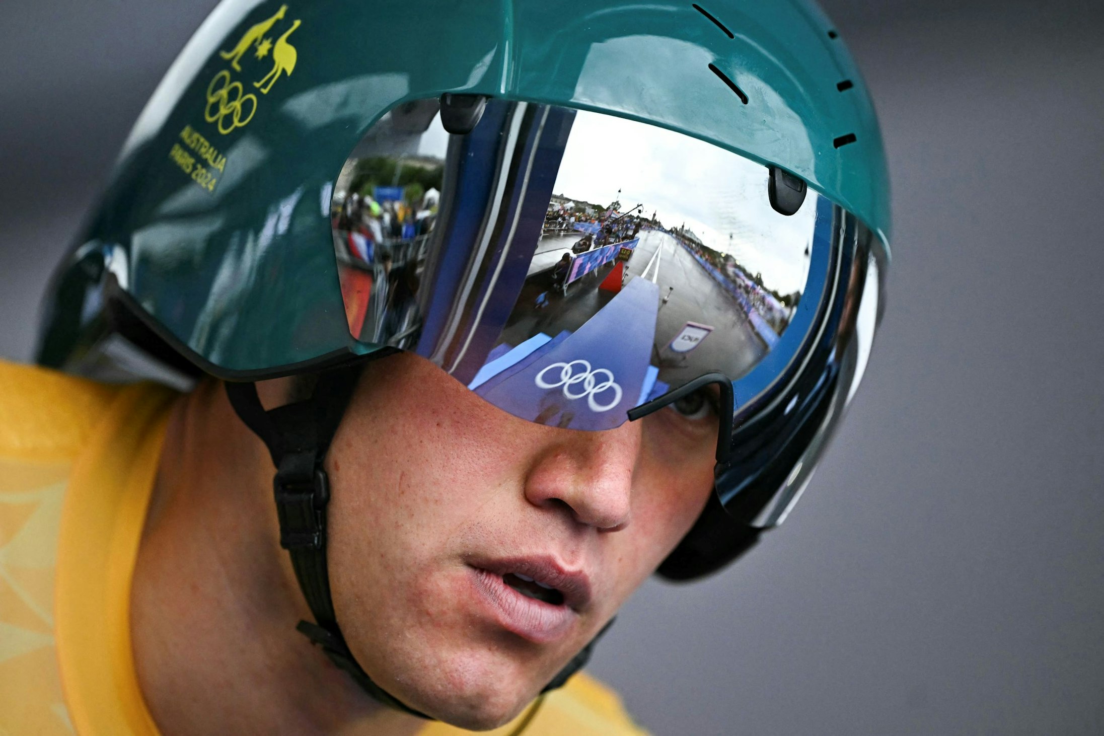 Australian cyclist Lucas Plapp looks down the start ramp of the Paris 2024 Olympic Games individual time trial, with the Olympic Rings on the start ramp reflected in his visor.