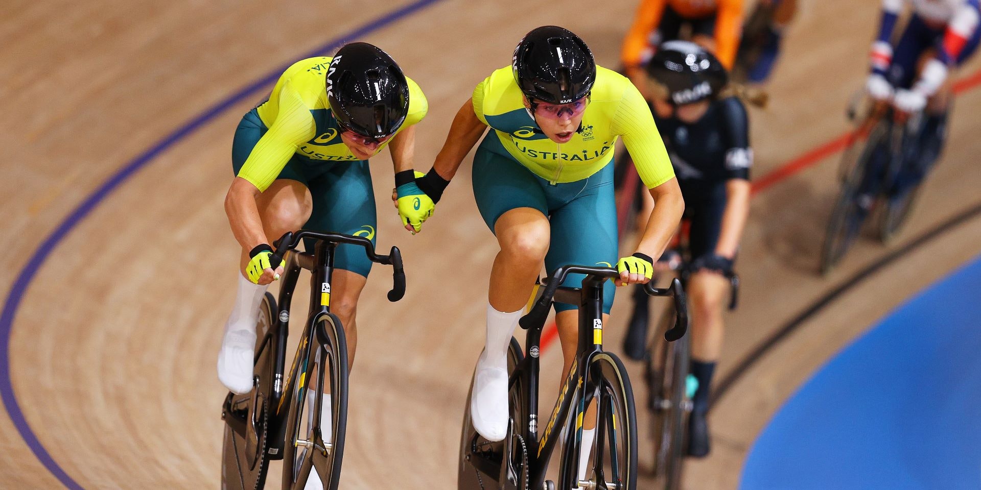 Two Australian track cyclists perform a handsling during the women's Madison race in the Tokyo 2020 Olympic Games track cycling program