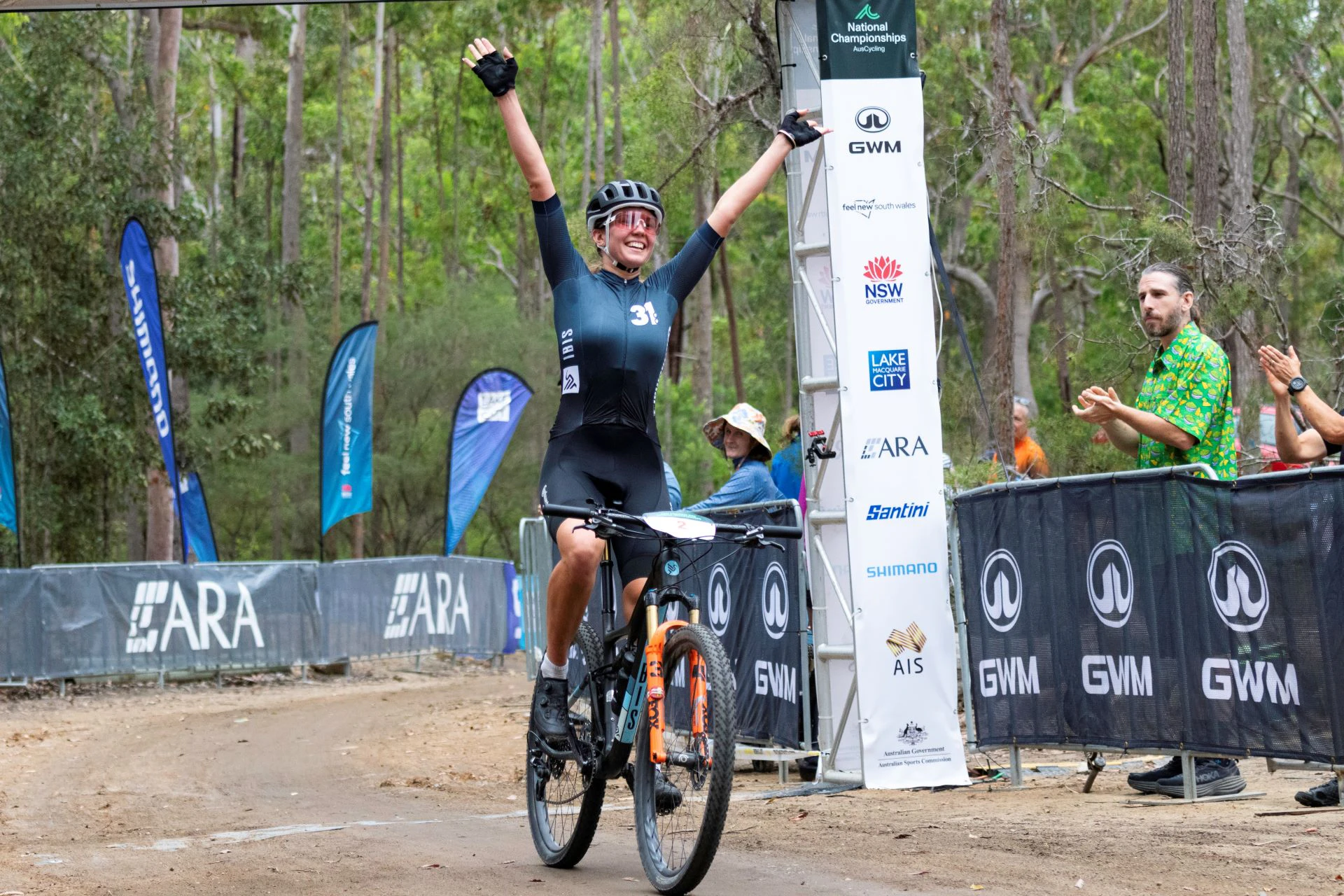 Australian cross-country mountain bike rider Zoe Cuthbert celebrates with arms raised as she crosses the finish line in the XCC short-course event at the 2024 GWM Mountain Bike National Championships in Awaba