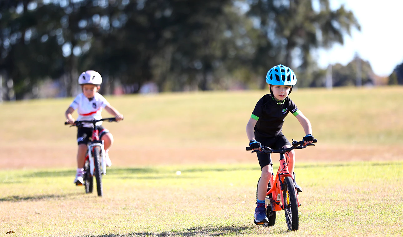 Two AusBike students riding through a park course