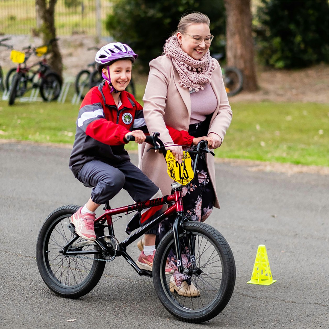 School student assisted with control of bike by a teacher