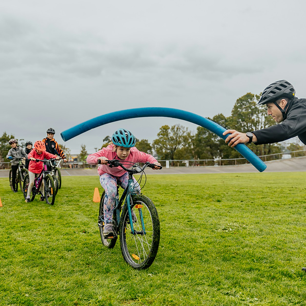 AusBike students ducking under instructor held foam noodle