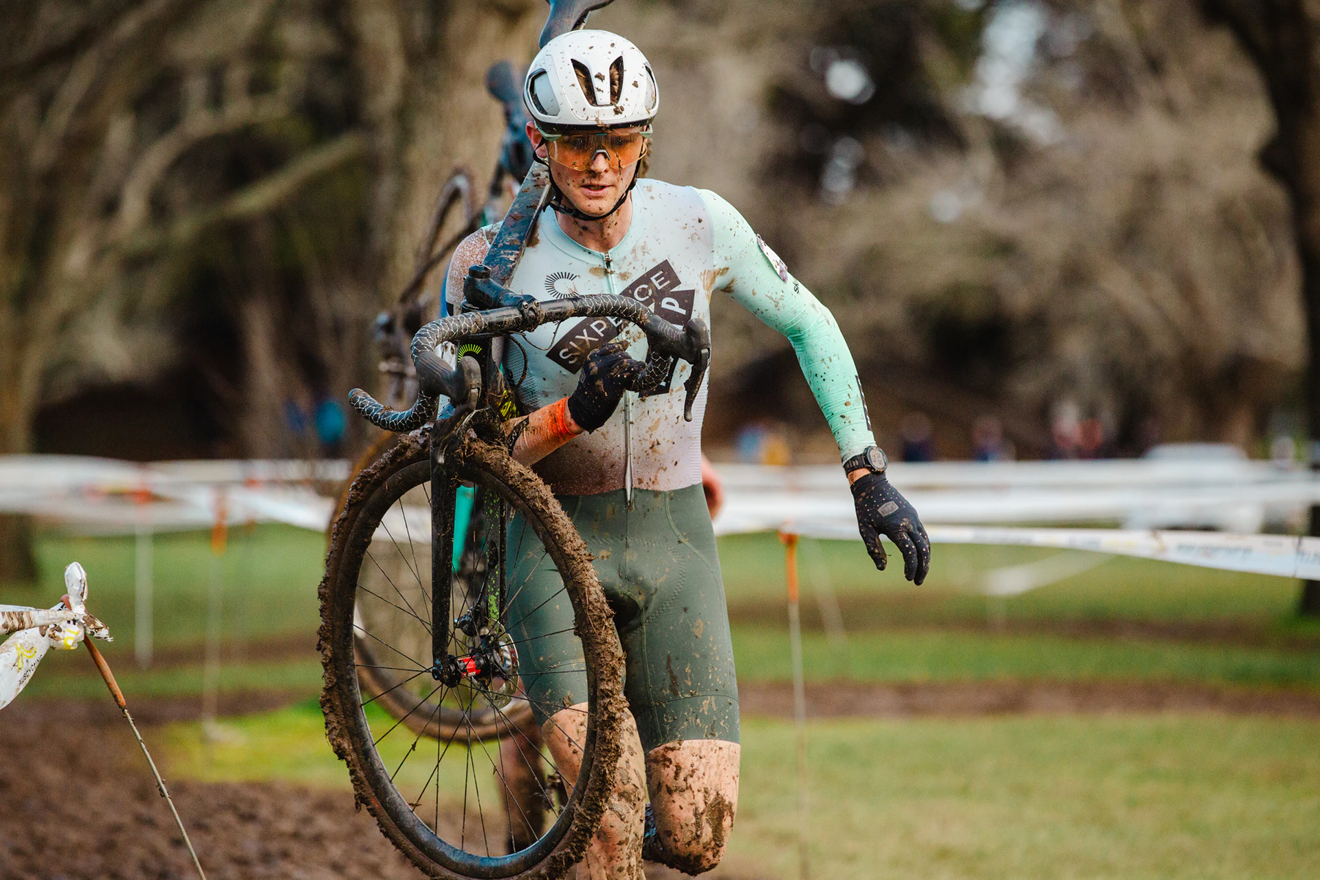 Cyclo-cross cyclist running through mud with bike