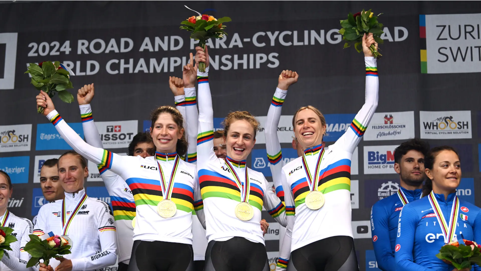 Ruby Roseman-Gannon, Grace Brown and Brodie Chapman in rainbow jerseys on the podium of the  team time trial mixed relay at the 2024 UCI Road World Championships in Zurich