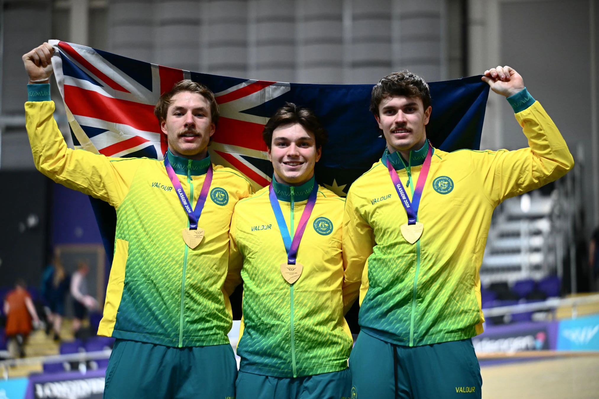 Australian Cycling Team's Ryan Elliott, Danny Barber and Leigh Hoffman pose with the Australian flag and gold medals after winning the Men’s Team Sprint at the 2026 Commonwealth Games in Glasgow, Scotland.